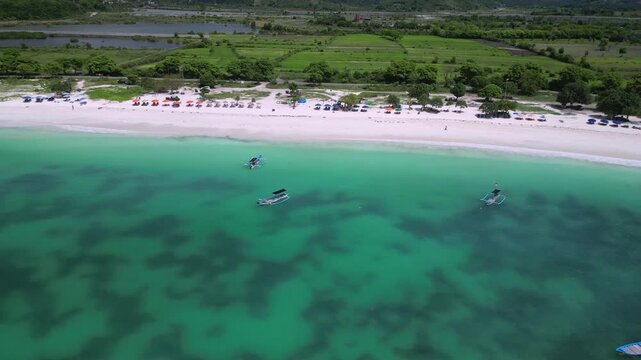 Aerial Coastline Dotted With Fishing Boats In Turquoise Water, Fleet Of Small Vessels Moving Along Shore, Fishermen Checking Nets, Calm Surf And Green Fields Beyond Beach, Tanjung Aan,Kuta,Lombok