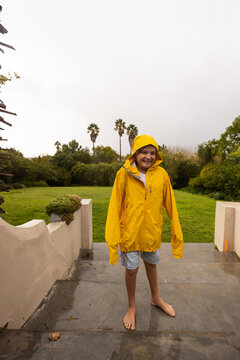 young boy wearing yellow raincoat enjoying the rain