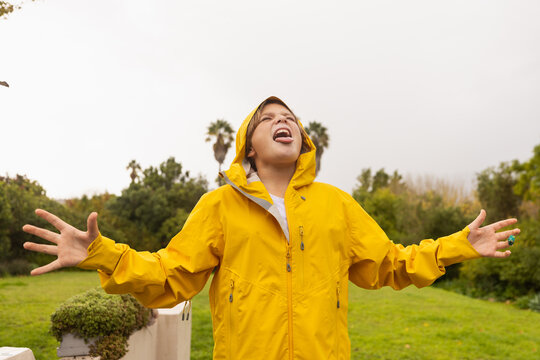young boy wearing yellow raincoat enjoying the rain