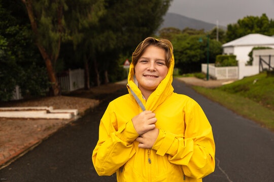 young boy wearing yellow raincoat enjoying the rain