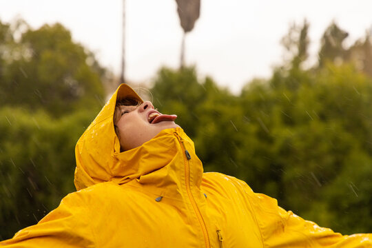 young boy wearing yellow raincoat enjoying the rain