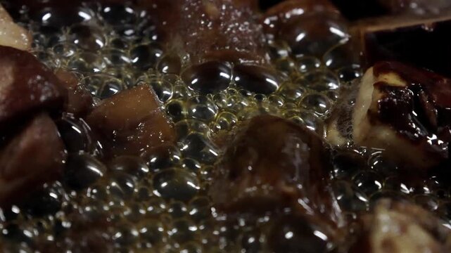 Cooking process of various mushrooms bubbling in hot oil, showcasing the gradual transformation and texture changes in a frying pan on a stovetop