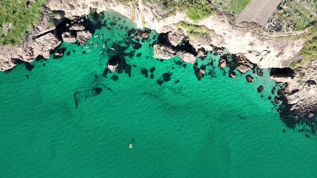 Cinematic Drone Descent and Rotation Revealing Maro Waterfall and Kayakers in Turquoise Sea Near Nerja, Spain