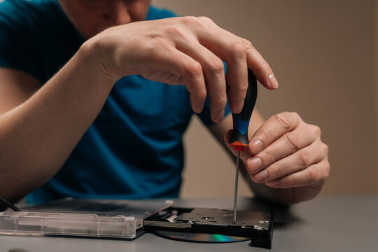 Technician repairing external optical disc drive, performing maintenance on the hardware, disassembling the casing of the cd dvd reader writer on a table.