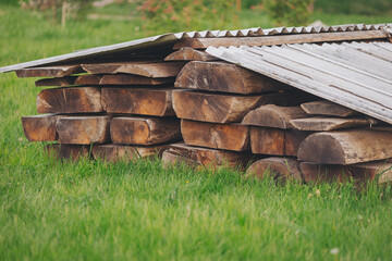 Obraz premium Wood logs stacked under a metal roof in a grassy area during daylight hours