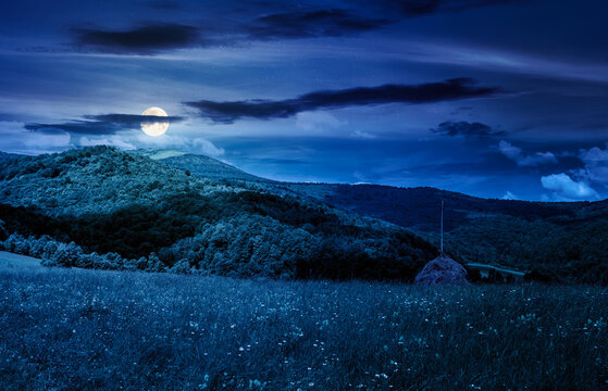 rural fields near pikui mountain in summertime at night. full moon over beautiful view of agricultural area. gorgeous mountain ridge with haystack on a grassy pasture. mysterious summer scenery