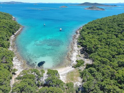 Adriatic sea rocky coastline with cleen turqouise sea and boats in the distance, aerial photo