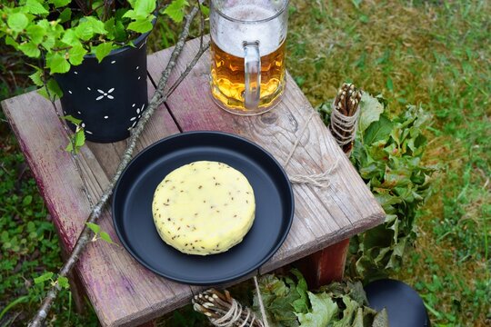 Midsummer celebration meal in a garden with traditional caraway cheese, beer and birch branches in black ceramic vase from a high angle