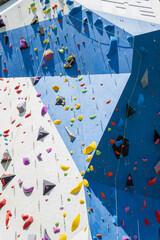 Obraz premium A mosaic of vibrant synthetic hand grips scattered across massive blue and white panels providing a challenging vertical playground for modern mountain sport enthusiasts