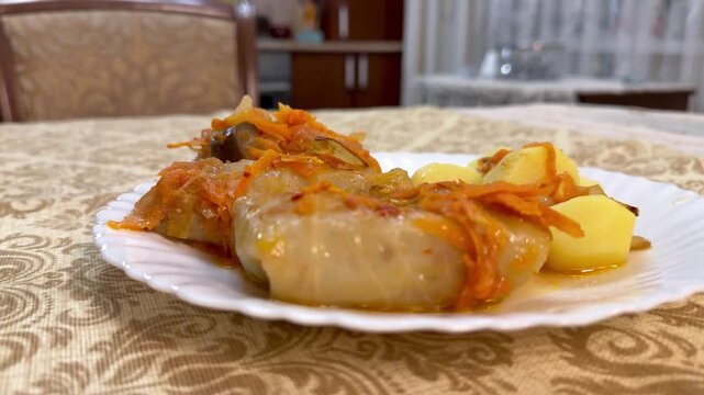 Cabbage rolls meat potatoes on plate, rustic homestyle serving on white plate over patterned tablecloth, warm tomato sauce glazing