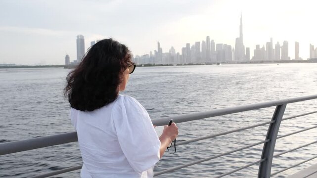 Woman journaling at sunset by waterfront while writing personal goals and reflections