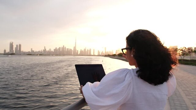 Female entrepreneur working remotely outdoors with laptop and Dubai city skyline