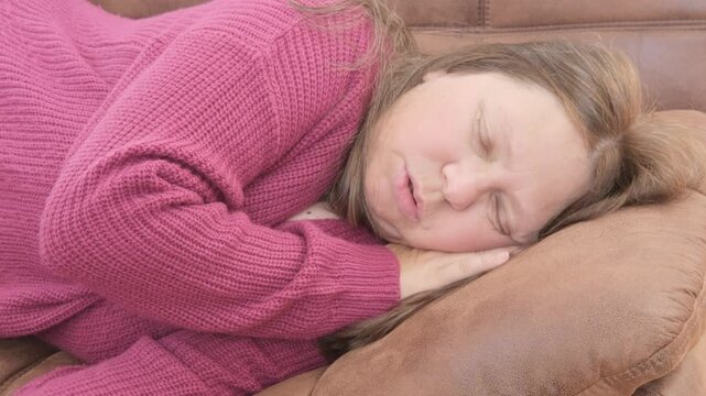 Overweight woman 50 sleeping on brown sofa during daytime, snoring, relaxed home environment, middle-aged, domestic scene, Daytime rest home showing natural sleep behavior mature woman, comfort zone
