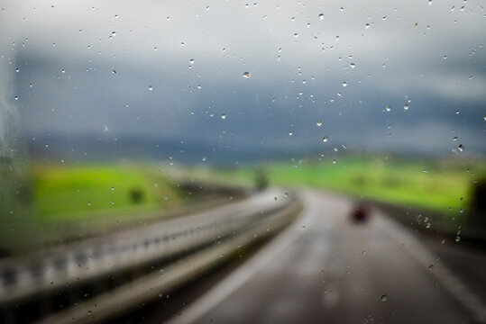 Window pane with raindrops and out of focus view of a motorway and countryside in the interior of Sicily between Syracuse and Catania, Sicily, Italy