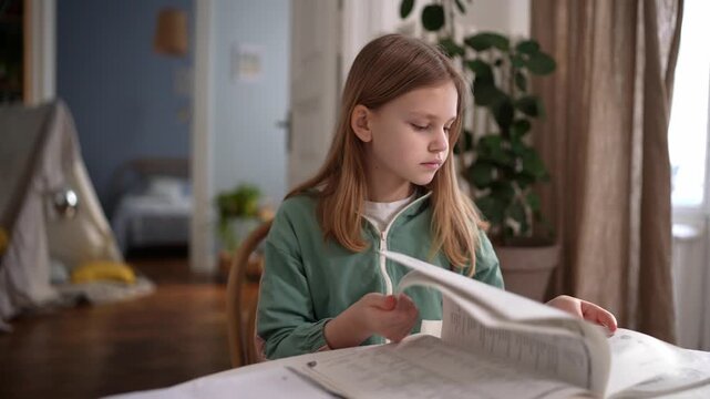 Young girl flipping through book pages at table, absorbed in reading and exploration, slow deliberate turns, curious concentrated expression, soft daylight, .