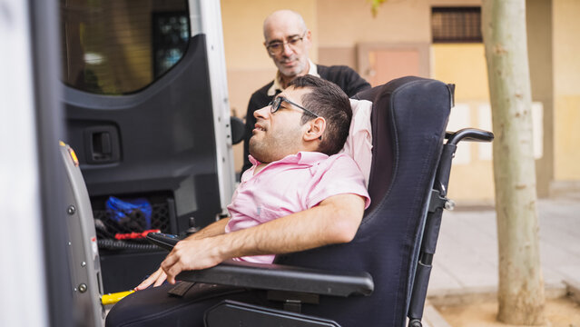 Man helping individual in a power wheelchair board a specialized vehicle with a ramp, promoting accessibility and inclusion