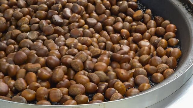 Close Up of Traditional Roasted Chestnuts Cooking in Large Metal Pan