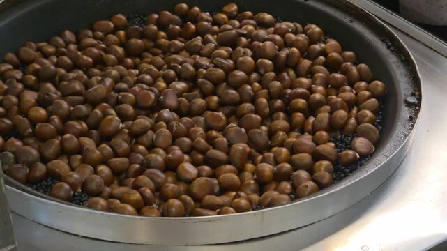 Process of roasting chestnuts in a big pan on the street market