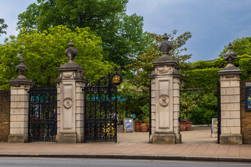 Fototapeta premium London, UK, 5 May 2026, Ornate black wrought iron gates at the entrance to Kew Gardens in London with stone pillars.