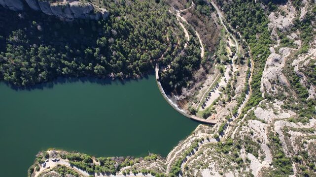 Bird's eye view aerial shot of Margalef dam and reservoir on sunny day. Tarragona Province, Spain.