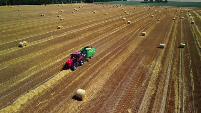 Preparing fodder for livestock. Mechanized straw baling for storage. A tractor working in a field in summer, and agricultural machinery. Agricultural work after the grain harvest.