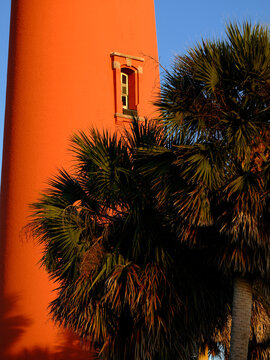 Tropical Palm tree at sunset  in front of the beautiful orange brick Ponce Island Lighthouse on the florida coast