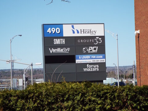 Gatineau, Quebec, Canada &ndash; April 18, 2026: A commercial pylon sign at 490 Boulevard Saint-Joseph displays tenant logos including "Groupe Heafey, VanillaSoft, and Forvis Mazars" against a blue sky.