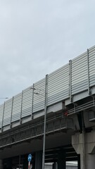 Obraz premium Modern elevated highway structure with sound barrier panels and urban infrastructure under cloudy sky