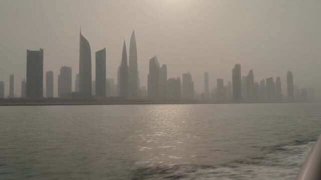 Kuwait City skyline seen from moving boat on hazy Persian Gulf waters