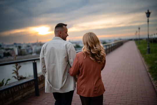 Couple walking together at sunset on city promenade