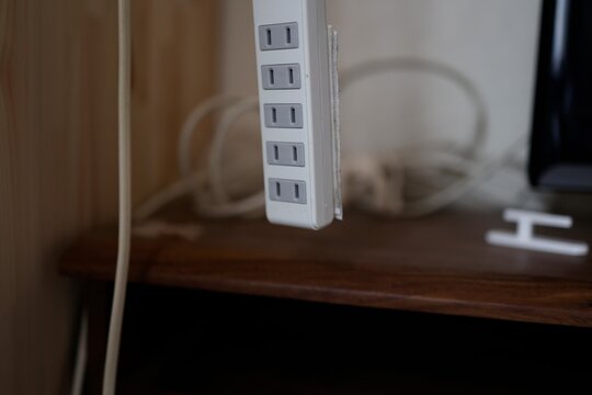 延長コンセント。白い5個口の電源タップが上から吊るされている。屋内