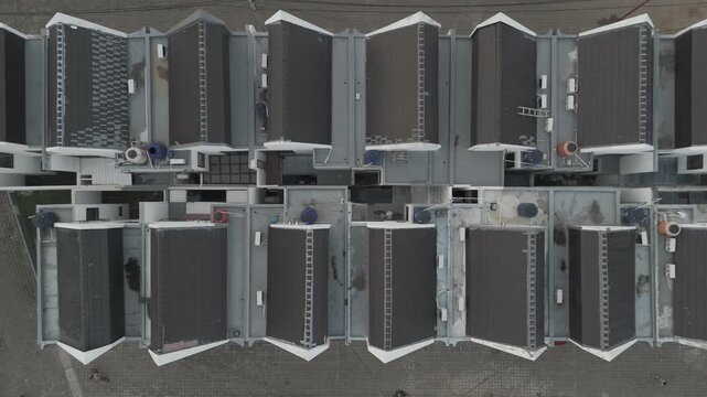 Shot in D-Log M for professional color grading Vertical top-down aerial perspective of organized modern housing units with grey tiled roofs in Jakarta.