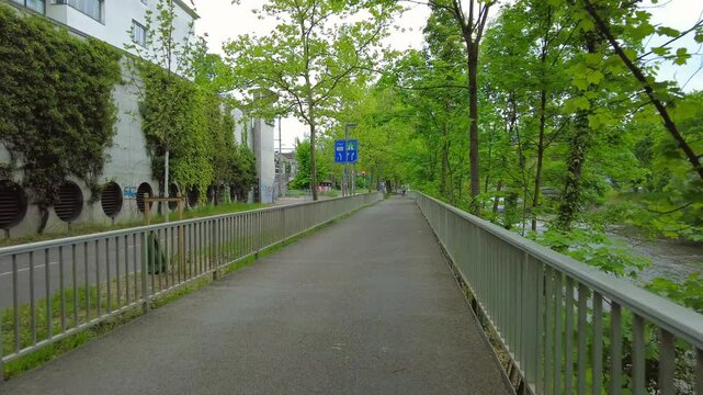 Pedestrian bridge path along Limmat river with ivy wall in Zurich