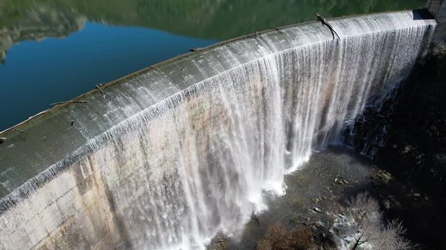 Tripod aerial shot of Margalef dam with water flowing through on sunny February day. Tarragona Province, Spain.
