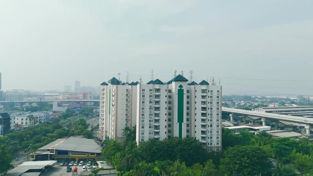 Vibrant aerial view of an apartment complex near a flyover bridge and industrial zone in Jakarta city.