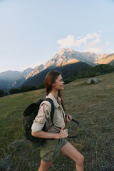 Fototapeta premium A woman hiker climbs a grassy hillside under a clear sky, with a backpack, embodying an active outdoors lifestyle and mountain exploration.