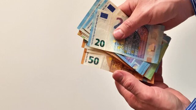 Mens Earnings in the European Union. stack of twenty and fifty euro banknotes held in a mans hands. 