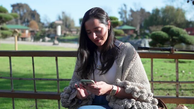 Beautiful woman sitting on a park bench puts on an asian conical hat and smiles at the camera