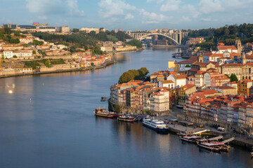 Obraz premium View from Miradouro da Serra do Pilar of Ribeira, Porto, Portugal, at sunrise with sunrise glow, boats on the river and Dom Luis I Bridge in the distance