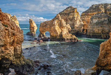 Clouds drift over Ponte da Piedade in Lagos, Algarve, Portugal, where ocean cliffs frame sea stacks and surf. © Dmitry Rukhlenko