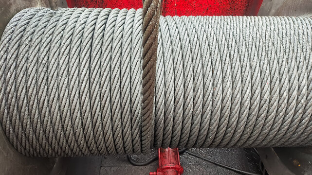 ​Close-up view of heavy-duty steel wire rope neatly coiled on a winch drum for industrial lifting and oil rig operations.