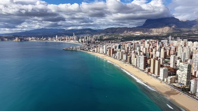 Aerial highrise beachfront and vibrant promenade with turquoise water, long sandy shore, bustling urban edge,