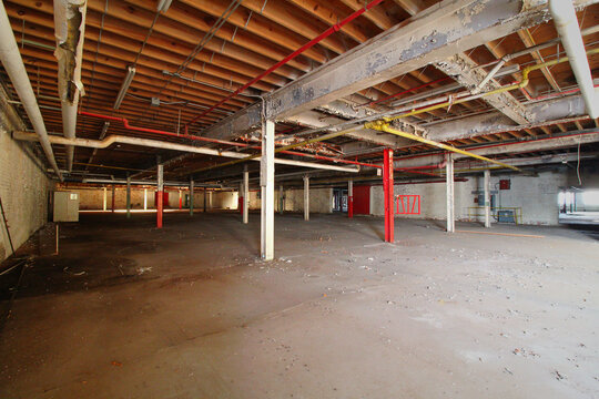Wide Empty Interior of Abandoned Warehouse with Wood Ceiling Joists and Red Pipes