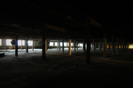 Vast Dark Interior of Abandoned Factory with Rows of Columns and Backlit Windows