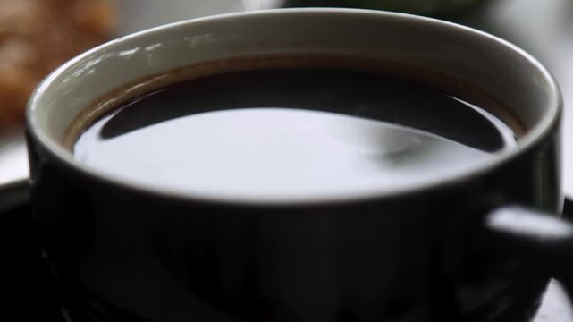 A cup of hot black coffee with a thin steam rising from it