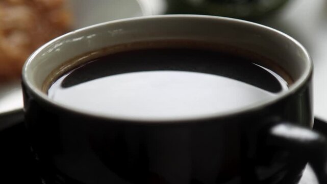 A cup of hot black coffee with a thin steam rising from it