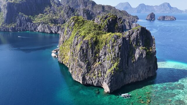 Surrounded by coral, rugged limestone islands rise from Bacuit Bay, El Nido. This area in the Philippines is a popular vacation destination due to its coral reefs, beaches, and limestone islands.
