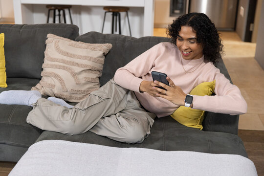 Person on gray sofa tapping phone starting animated tech overlay highlighting kitchen