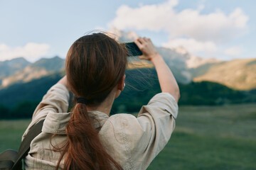 Obraz premium Woman outdoors photographs mountains with a camera, showcasing lifestyle photography in a natural landscape, peaceful adventurous mood, focus on exploration and scenery