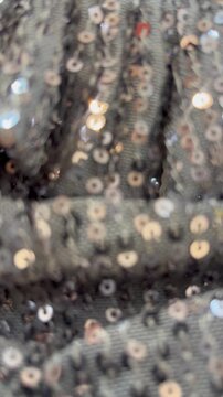 Close-up of shimmering bronze sequins on black fabric background